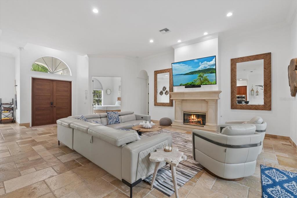 A spacious living room features a stone fireplace, a large sectional sofa, and tile flooring — 3508 LA PALOMA AVENUE, SARASOTA, FL