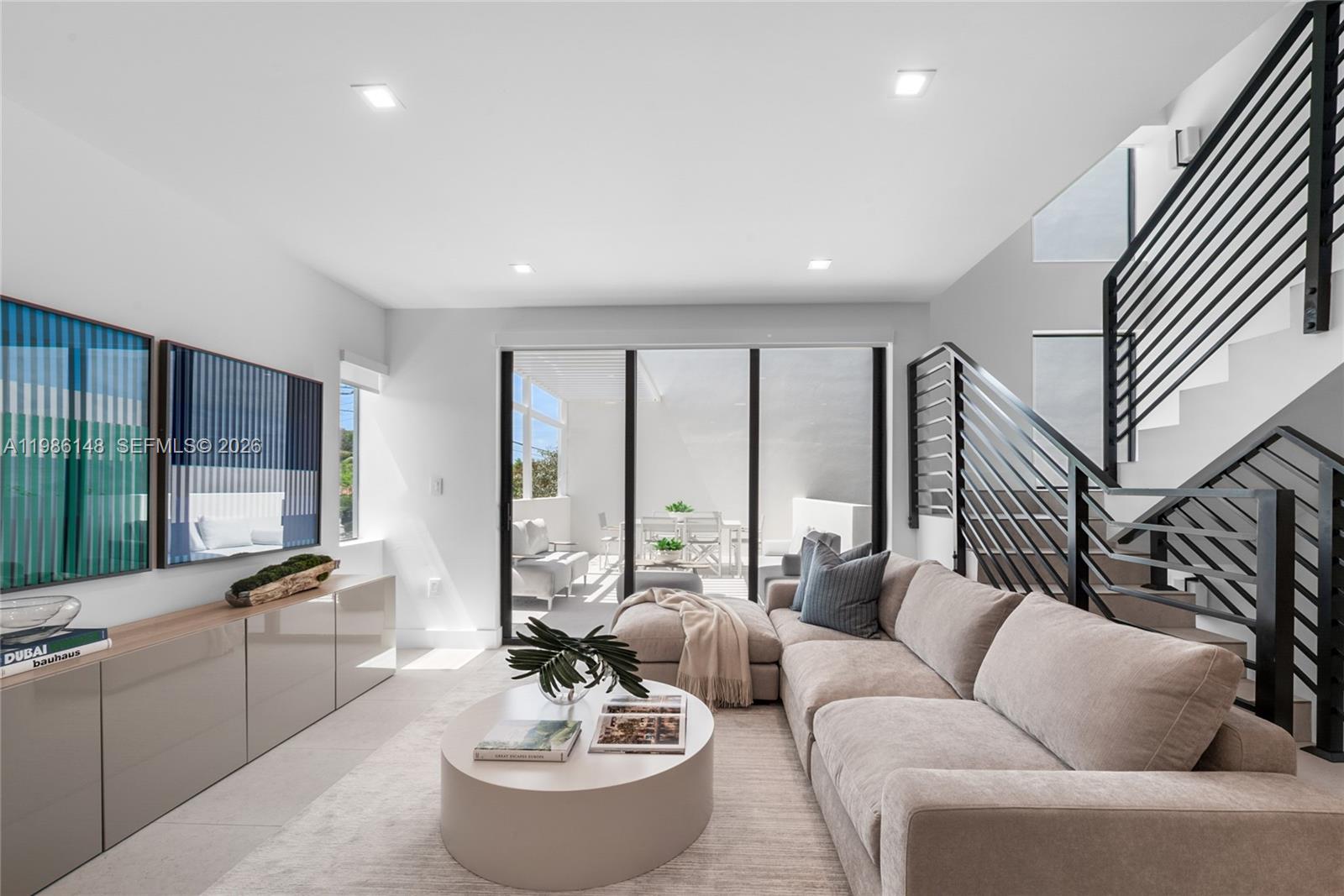 A modern living room features a sectional sofa, a round coffee table, and a staircase — 721 SW 11th Street # A, Miami FL 33129, MIAMI, FL