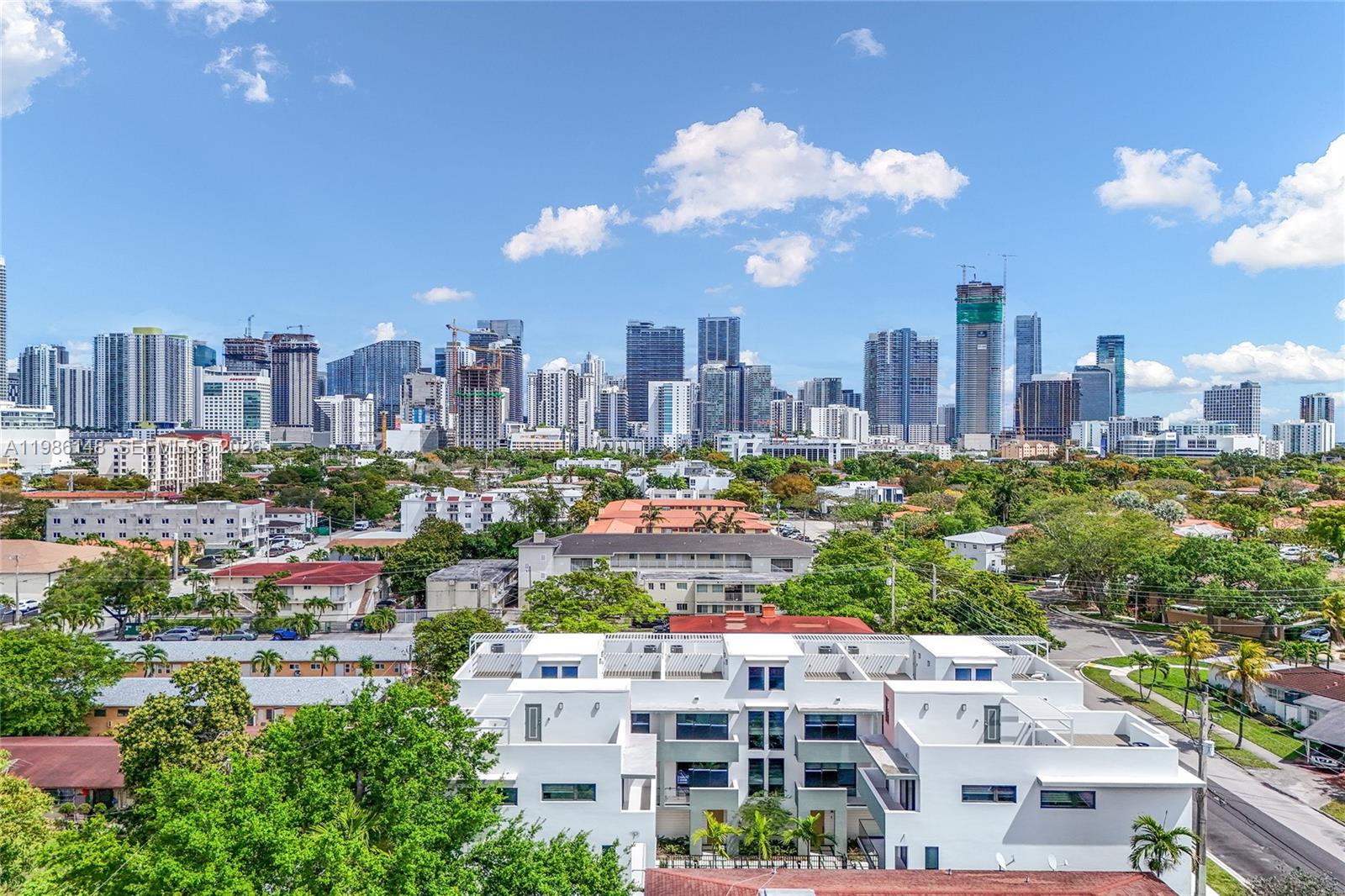An aerial view shows a modern white apartment building in front of a city skyline — 721 SW 11th Street # A, Miami FL 33129, MIAMI, FL