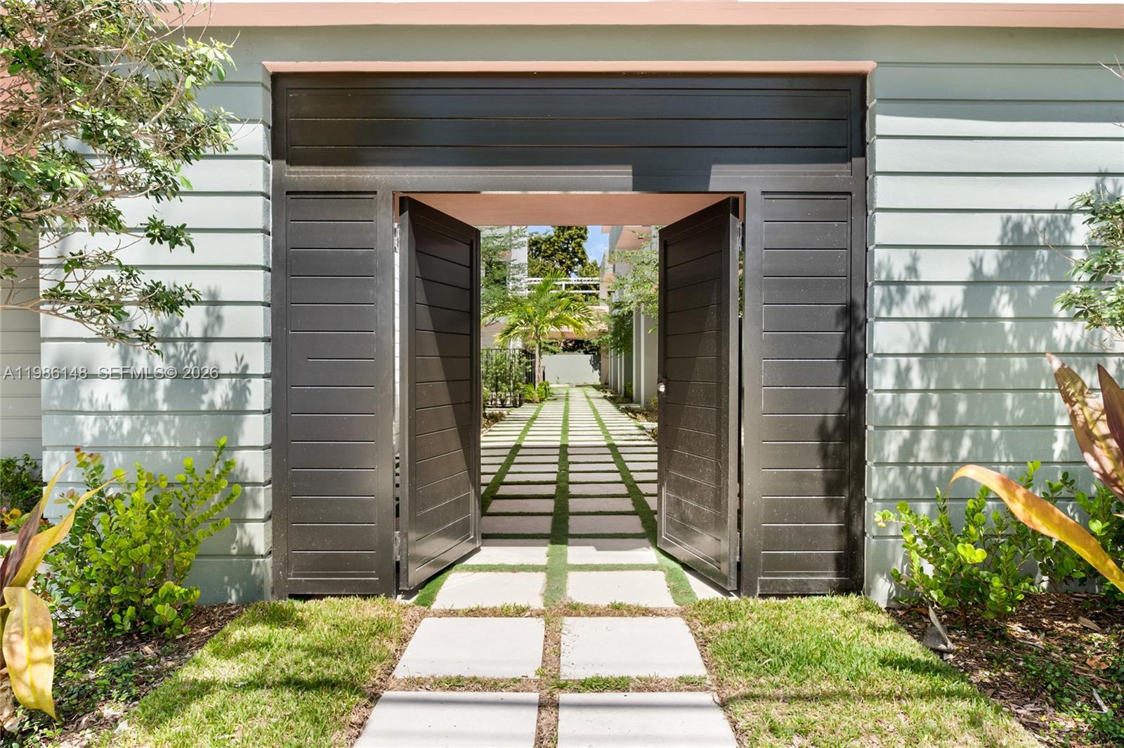 A pair of open dark wooden gates leads to a stone-paved walkway outdoors — 721 SW 11th Street # A, Miami FL 33129, MIAMI, FL