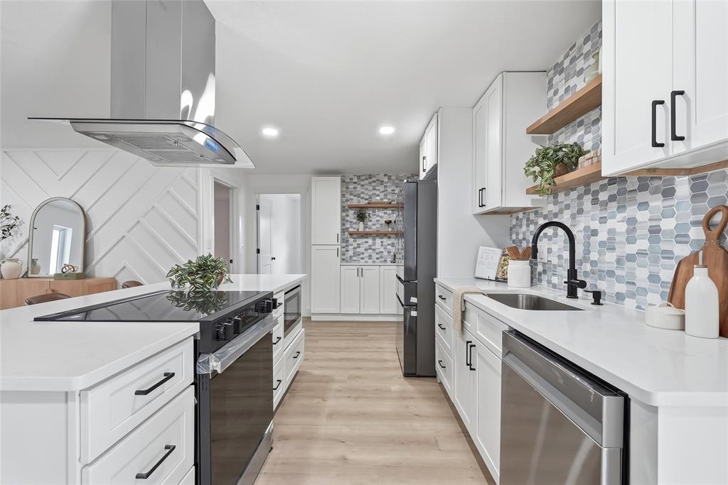 A modern kitchen features white cabinets, a hexagon tile backsplash, and a stainless steel range — 6419 PELICAN DRIVE S, ST PETERSBURG, FL