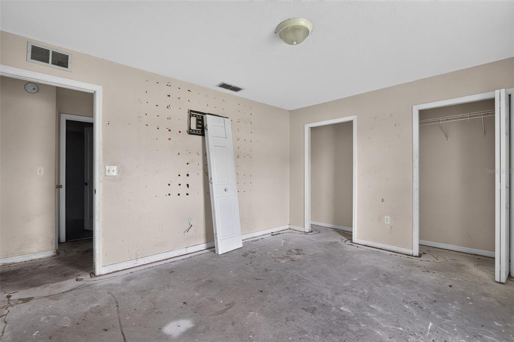 An empty room with beige walls, a concrete floor, and two open doorways — 28 PECAN RUN WAY, OCALA, FL