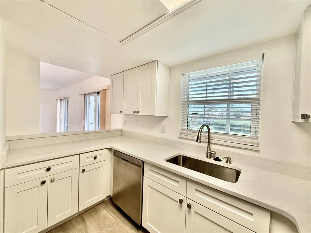 A kitchen features white cabinets, light countertops, a stainless steel sink, and a window — 8801 BAY POINTE DRIVE UNIT 102, TAMPA, FL