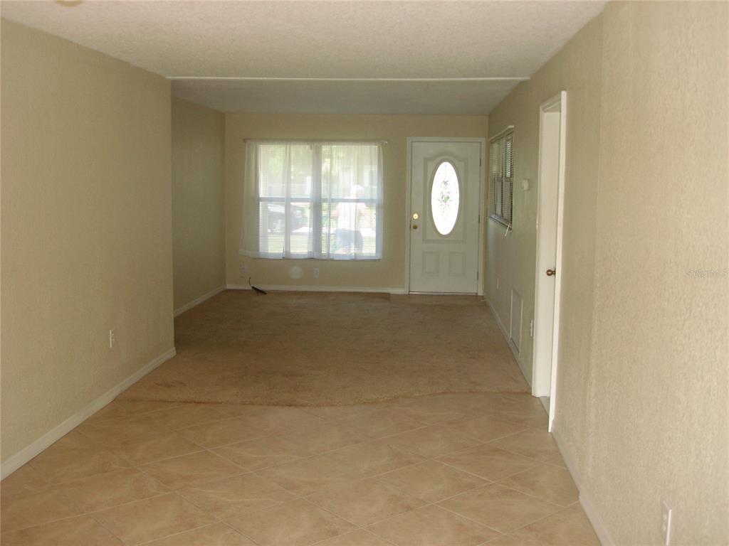 A living room features beige carpet, tile flooring, a front door, and a large window — 1300 PARK AVENUE, TAVARES, FL