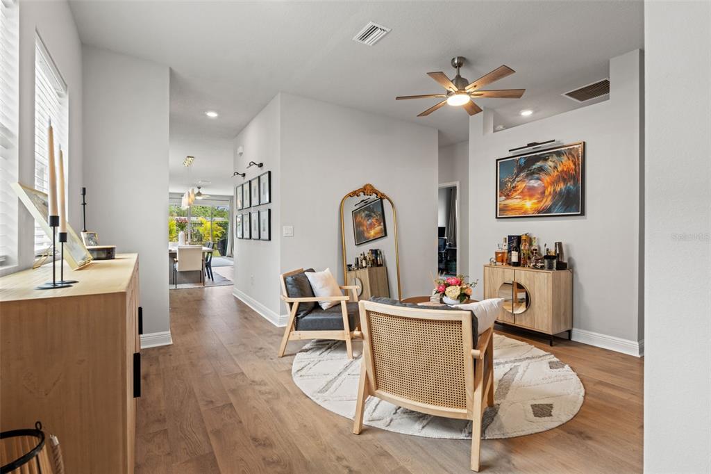 A living area features wood flooring, two armchairs on a rug, and a bar cabinet — 5607 DEL CORONADO, APOLLO BEACH, FL