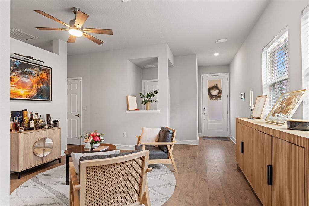 A living room features light wood flooring, a ceiling fan, and two wooden accent cabinets — 5607 DEL CORONADO, APOLLO BEACH, FL