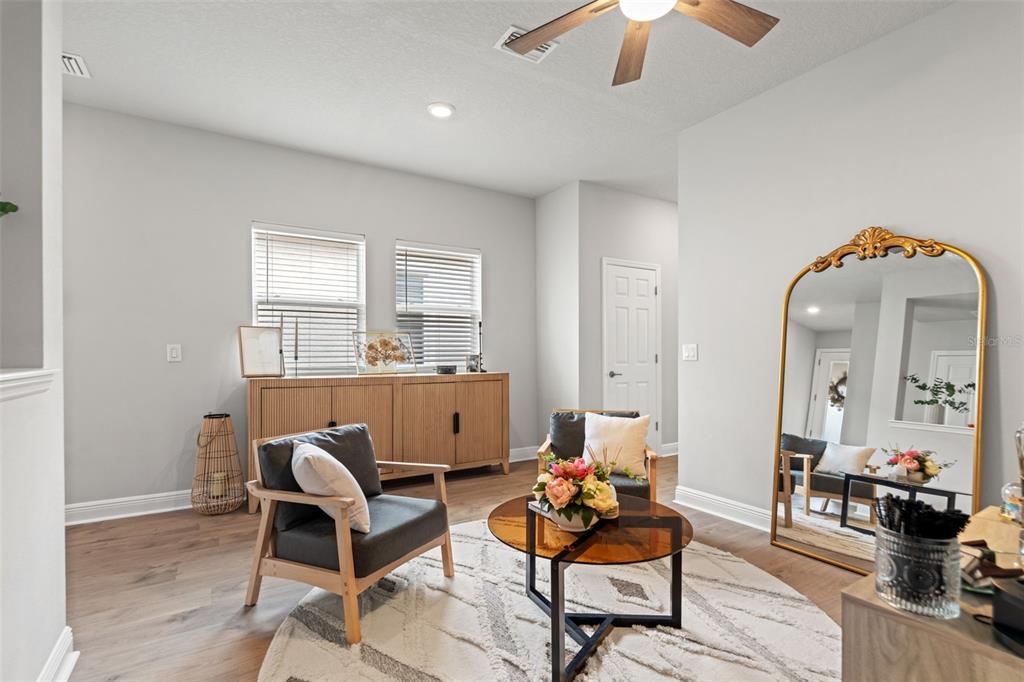 A living room features two armchairs, a round coffee table, a credenza, and a floor mirror — 5607 DEL CORONADO, APOLLO BEACH, FL
