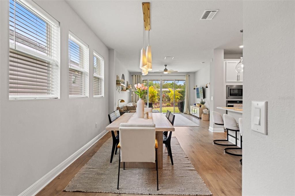 A dining area with a wooden table and chairs sits adjacent to an open living room — 5607 DEL CORONADO, APOLLO BEACH, FL