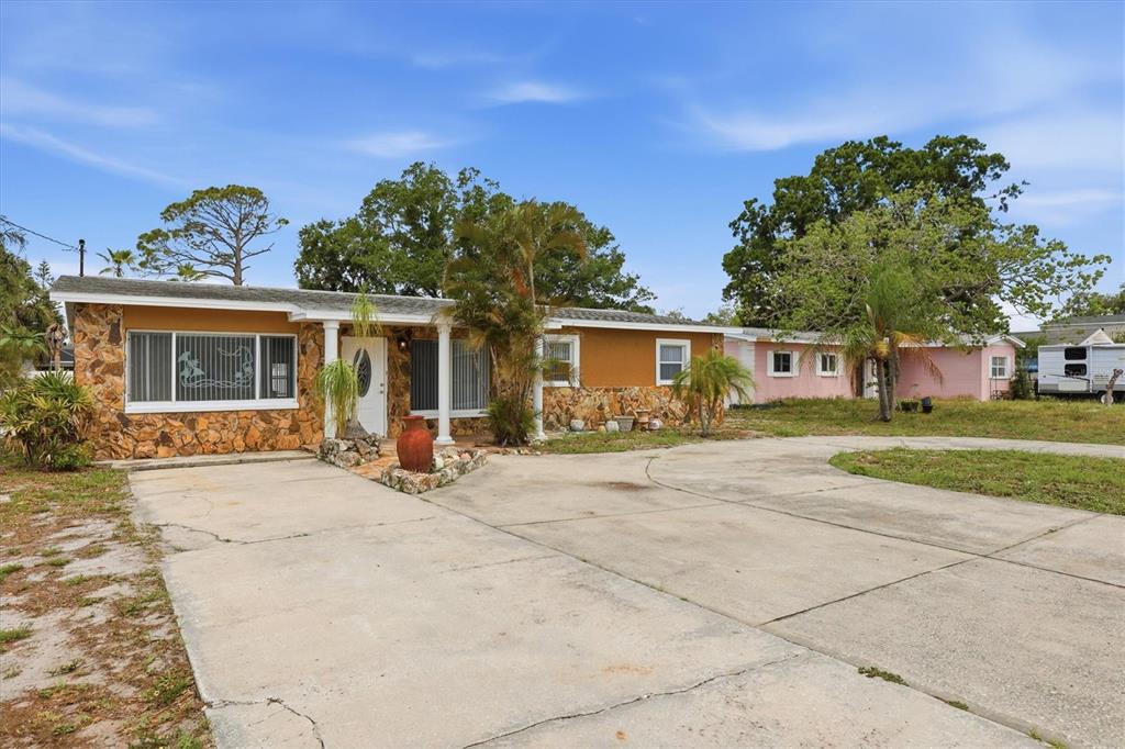 A single-story house with a stone facade and a large concrete driveway — 721 BAYSHORE DRIVE, TARPON SPRINGS, FL