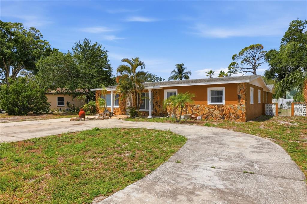A single-story house with a stone facade and a curved concrete driveway — 721 BAYSHORE DRIVE, TARPON SPRINGS, FL