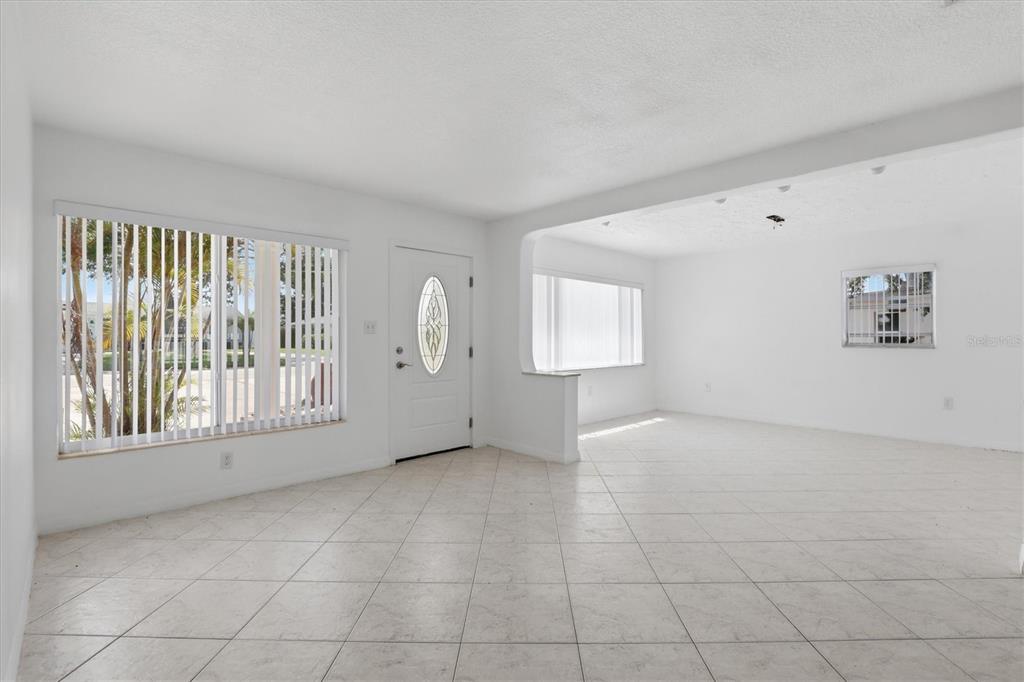 An empty living room features white walls, light-colored tile flooring, and a front entry door — 721 BAYSHORE DRIVE, TARPON SPRINGS, FL