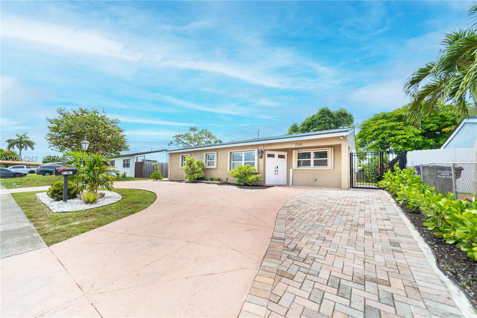 A single-story house with a paved driveway and a front yard featuring palm trees — 7101 Hope St, Hollywood FL 33024, HOLLYWOOD, FL