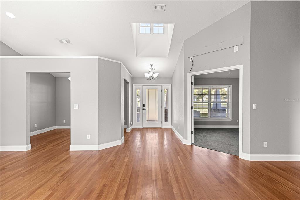 An entryway with hardwood floors, a skylight, a chandelier, and doorways leading to other rooms — 10485 SE 42ND COURT, BELLEVIEW, FL
