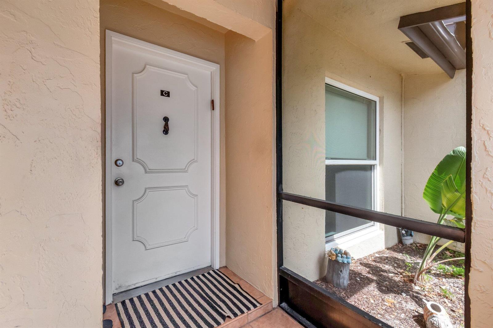 A white front door with a letter C label sits beside a screened-in entryway — 13691 Via Aurora, Delray Beach FL 33484, DELRAY BEACH, FL