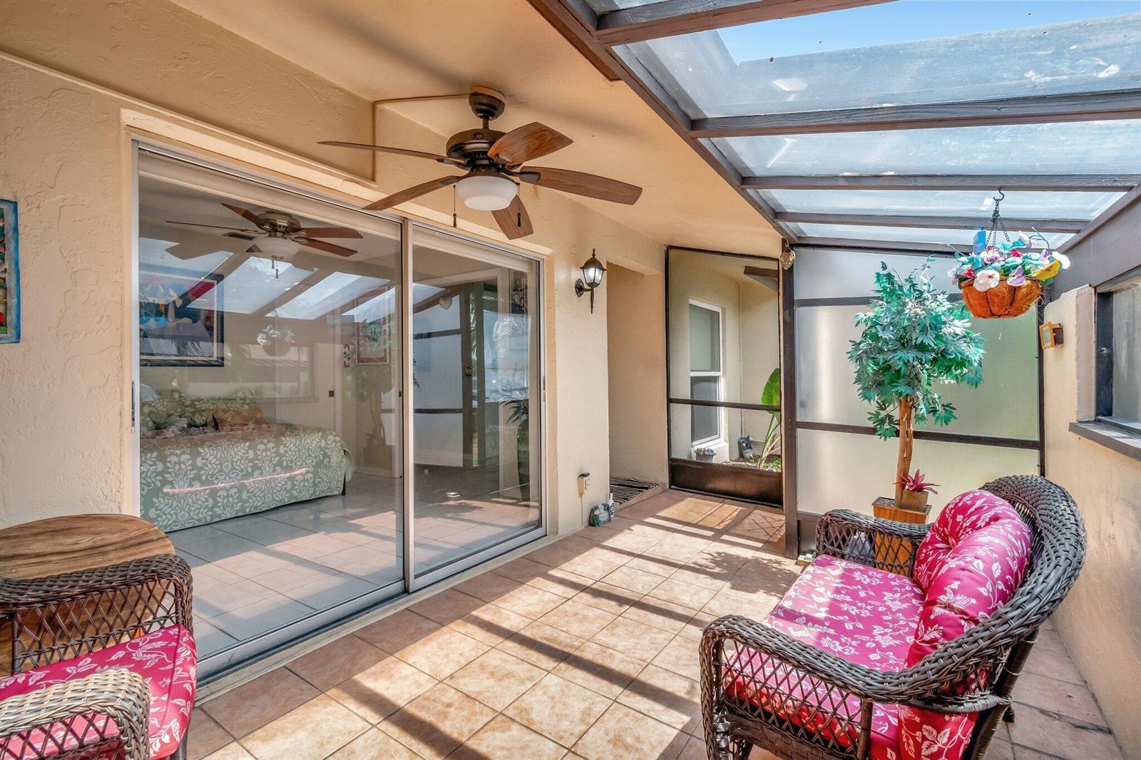 A sunroom with a glass roof, tiled floor, wicker furniture, and sliding glass doors — 13691 Via Aurora, Delray Beach FL 33484, DELRAY BEACH, FL