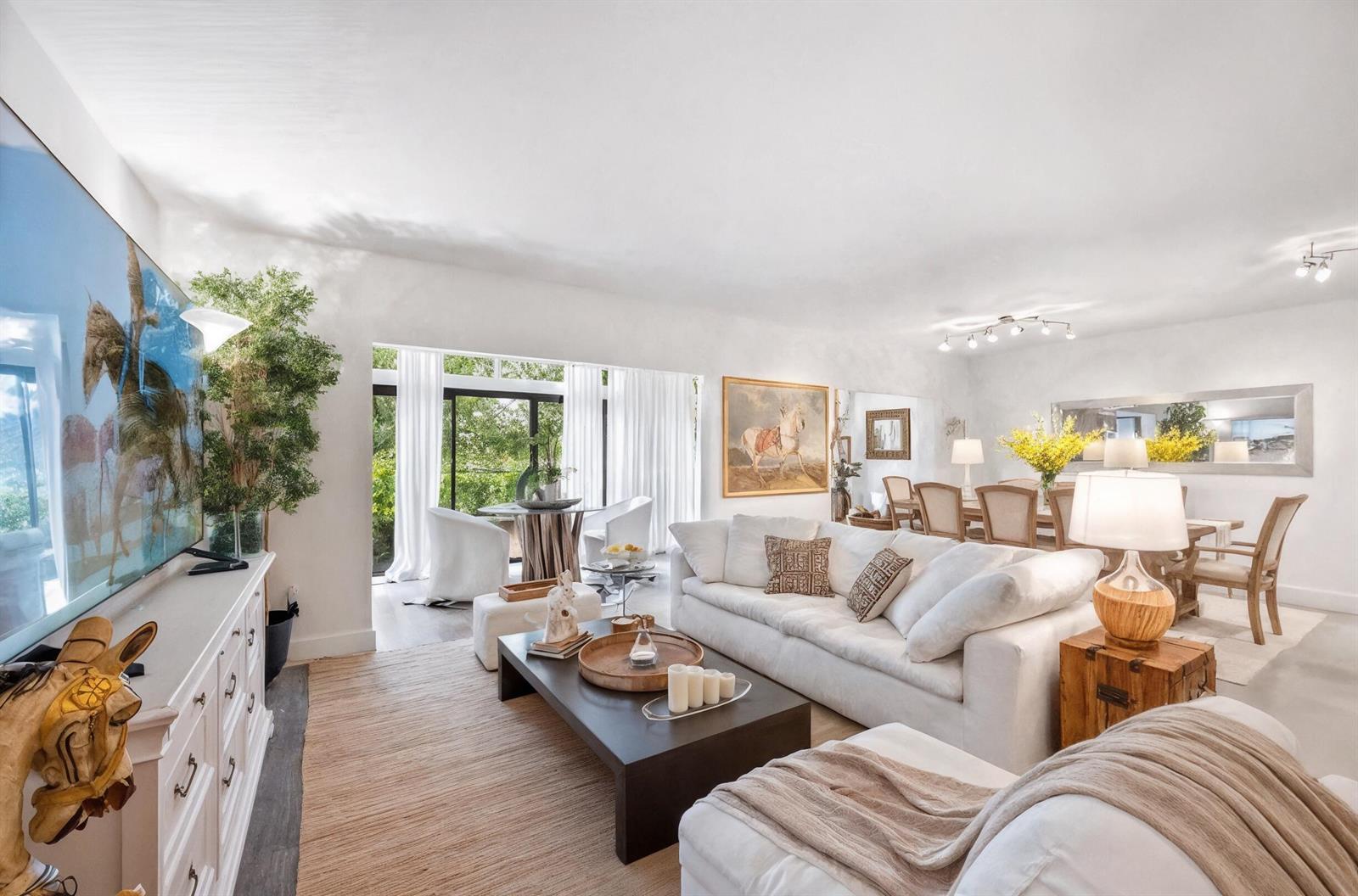 A bright, open-concept living and dining room features white furniture, a dark coffee table, and large windows — 11397 Pond View Drive # E103, Wellington FL 33414, WELLINGTON, FL