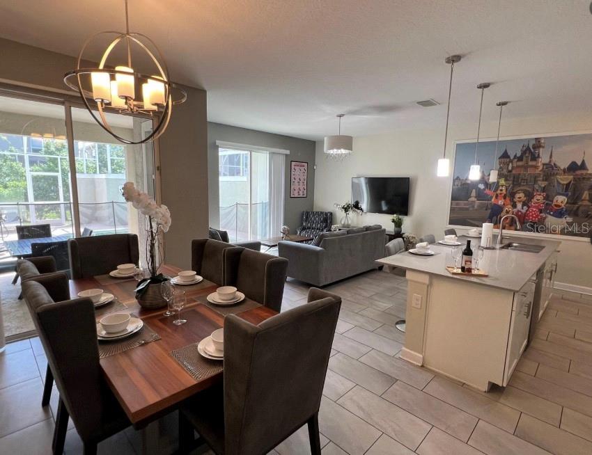 An open-concept dining area and kitchen feature a wooden table, island, and tile flooring — 420 OCEAN COURSE AVENUE, DAVENPORT, FL