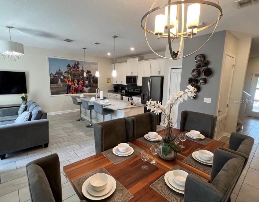 An open-concept kitchen and dining area features a wooden table, island seating, and tile flooring — 420 OCEAN COURSE AVENUE, DAVENPORT, FL