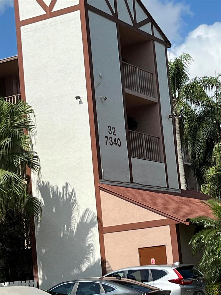 Exterior view of a multi-story apartment building with balconies and a brown shingled roof — 7340 Amberly Lane # 205, Delray Beach FL 33446, DELRAY BEACH, FL