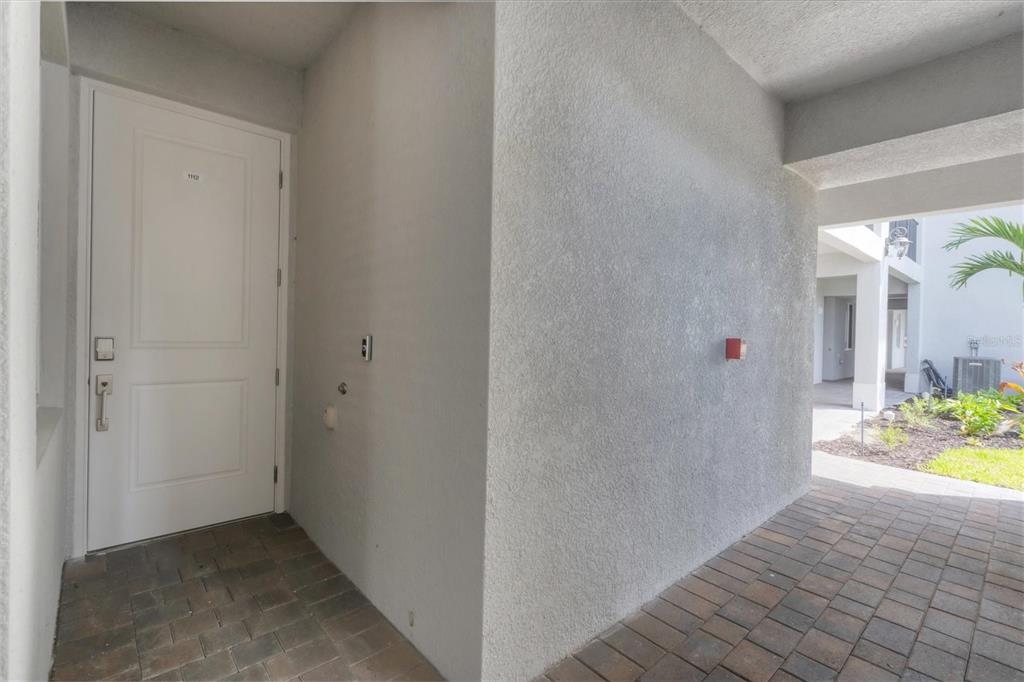 A white front door opens onto a paved entryway with a textured stucco wall — 14161 HERITAGE LANDING BOULEVARD UNIT 1112, PUNTA GORDA, FL