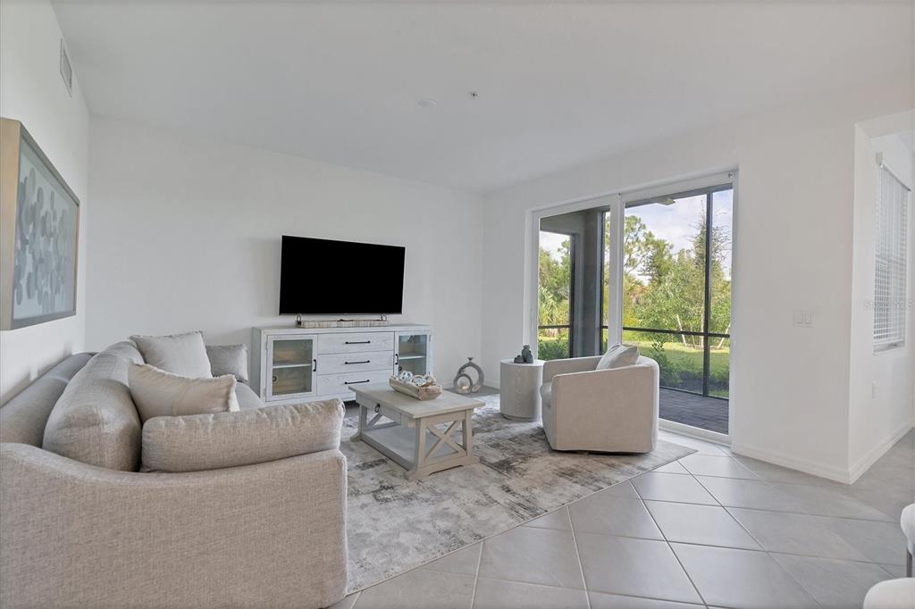 A living room with a sofa, television, coffee table, and sliding glass doors to a patio — 14161 HERITAGE LANDING BOULEVARD UNIT 1112, PUNTA GORDA, FL