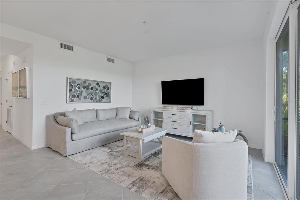 A living room features a gray sofa, a white coffee table, and a television console — 14161 HERITAGE LANDING BOULEVARD UNIT 1112, PUNTA GORDA, FL