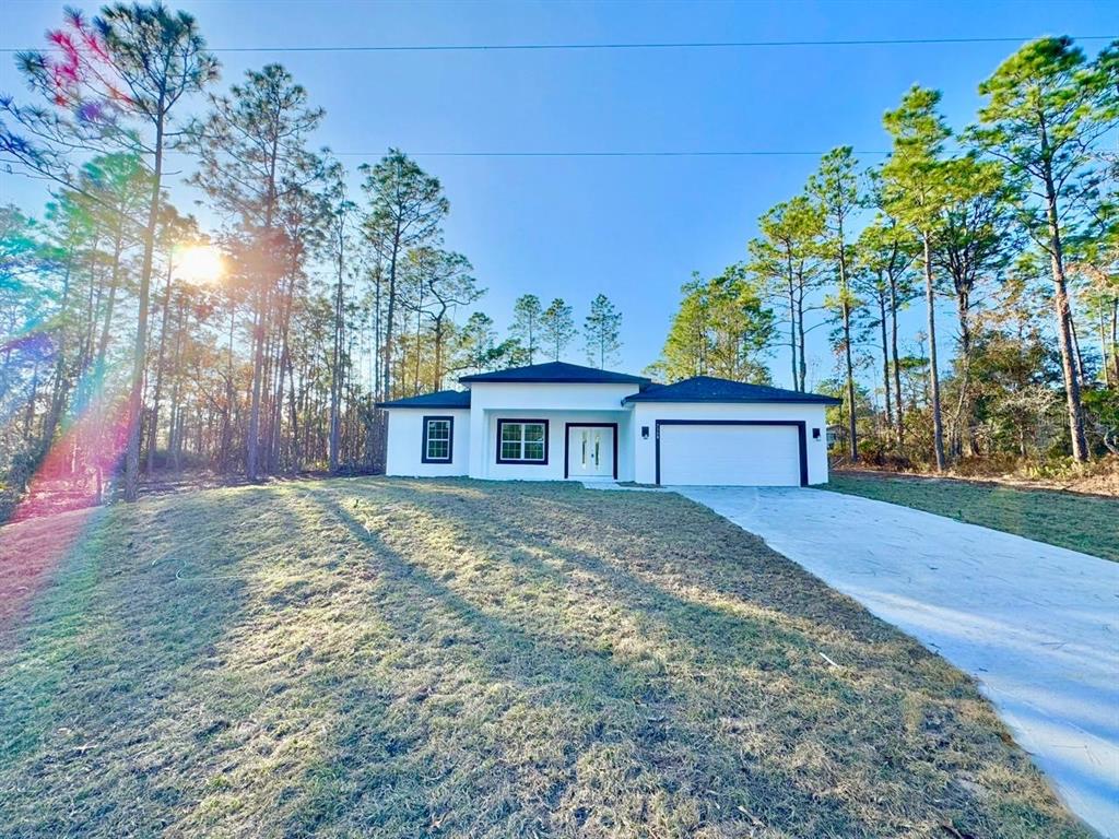 A modern, white single-story house with a dark roof and garage sits on a grassy lot — 7168 N DEBORAH TERRACE, CITRUS SPRINGS, FL