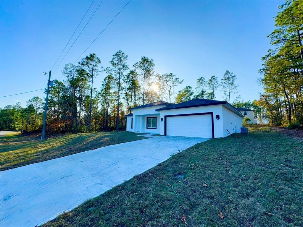 A white single-story house with a two-car garage sits on a grassy lot — 7168 N DEBORAH TERRACE, CITRUS SPRINGS, FL