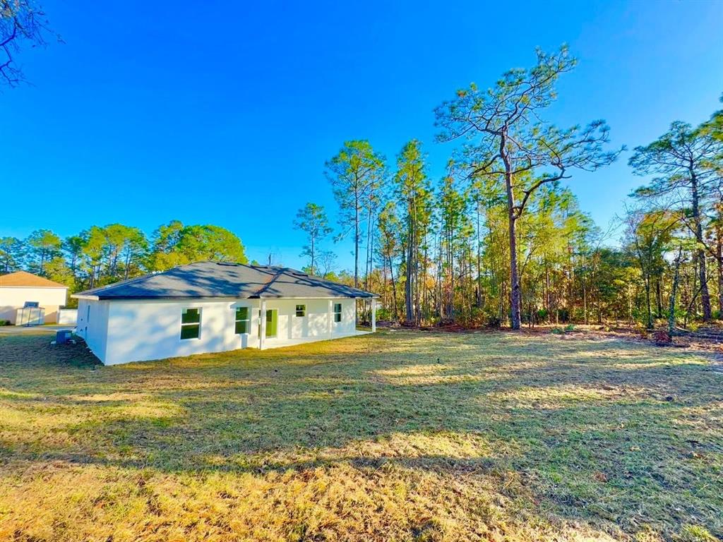 A white house with a dark roof sits on a large, grassy lot near trees — 7168 N DEBORAH TERRACE, CITRUS SPRINGS, FL