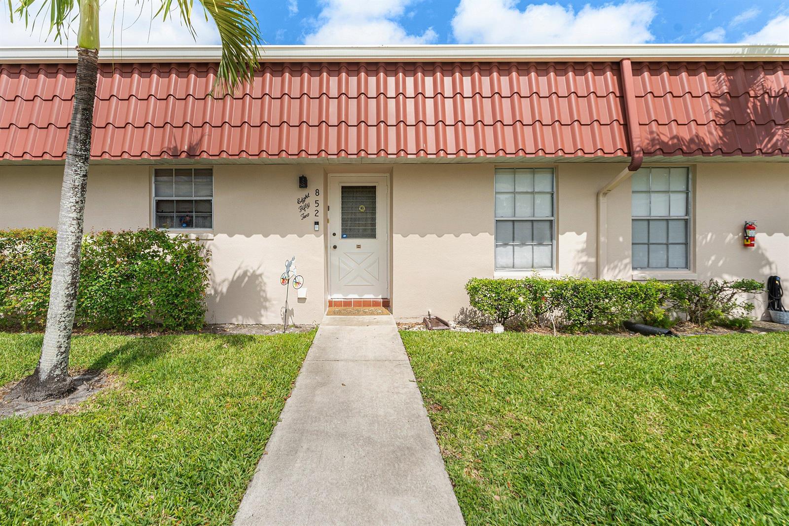 A beige exterior wall features a front door, two windows, and a red tiled roof — 852 Salem Lane, Lake Worth FL 33467, LAKE WORTH, FL