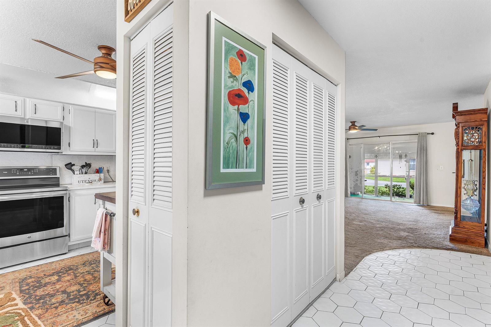 A kitchen with white cabinets and a tiled floor opens into a carpeted living area — 852 Salem Lane, Lake Worth FL 33467, LAKE WORTH, FL