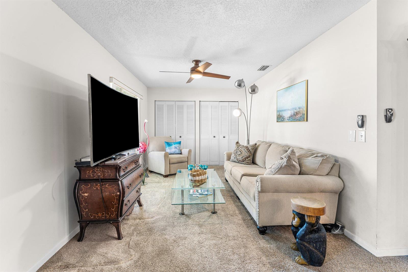 A living room features a beige sofa, glass coffee table, television on a dresser, and carpet — 852 Salem Lane, Lake Worth FL 33467, LAKE WORTH, FL