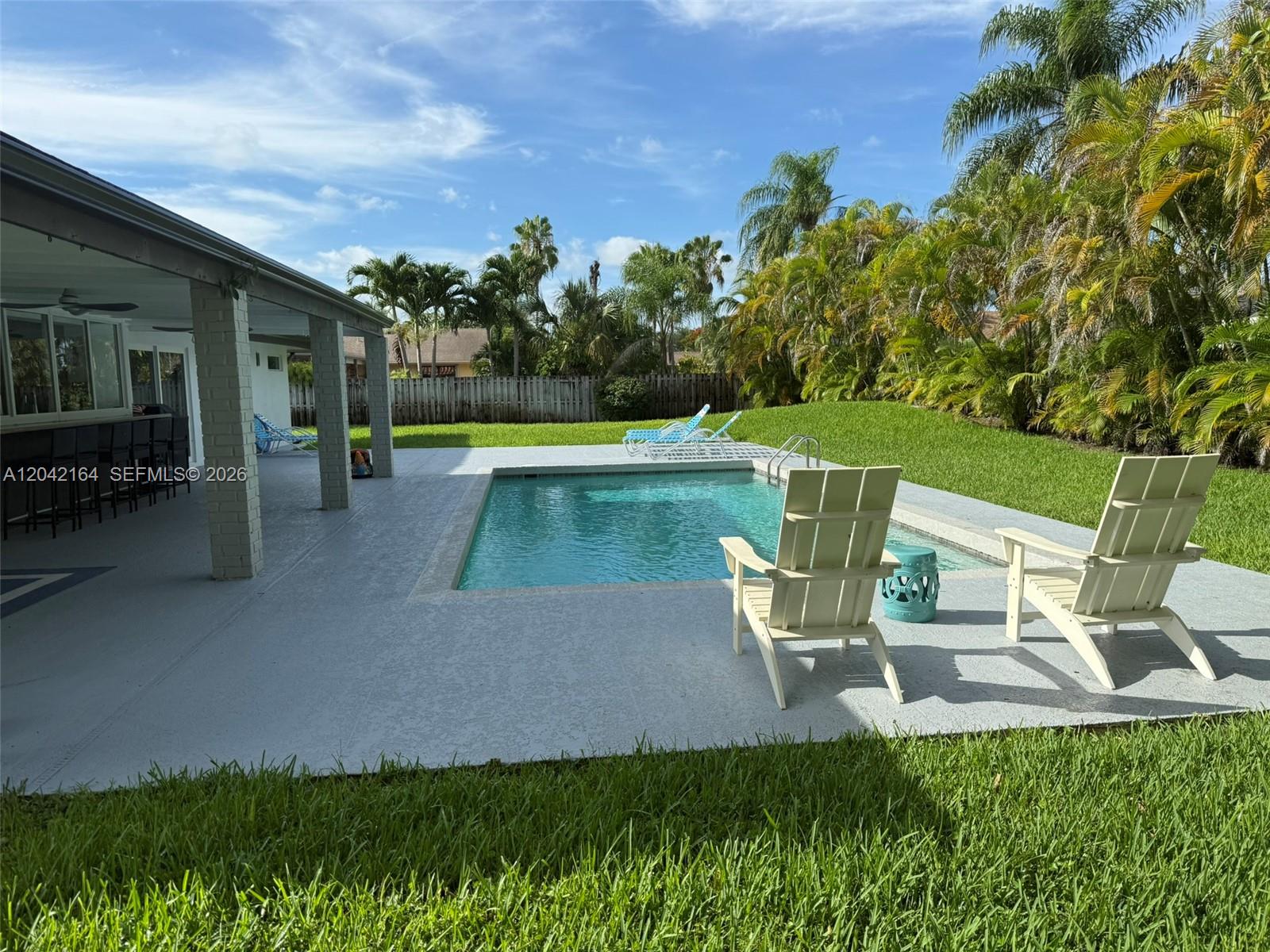 A backyard features a swimming pool, patio, and lawn with palm trees and lounge chairs — 13461 SW 98th Pl # 13461, Miami FL 33176, MIAMI, FL