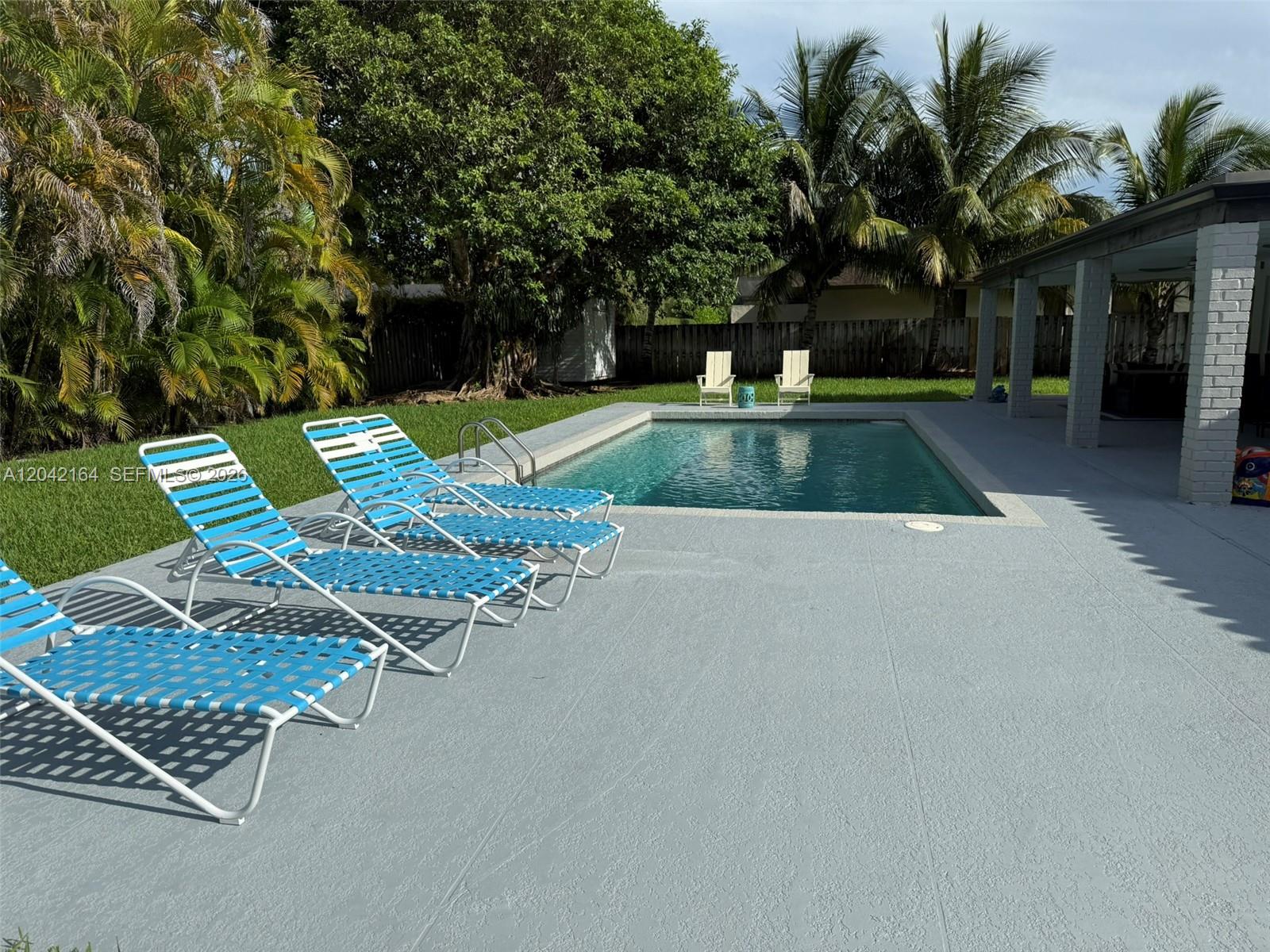 A backyard features a rectangular swimming pool, lounge chairs, and a covered patio area — 13461 SW 98th Pl # 13461, Miami FL 33176, MIAMI, FL