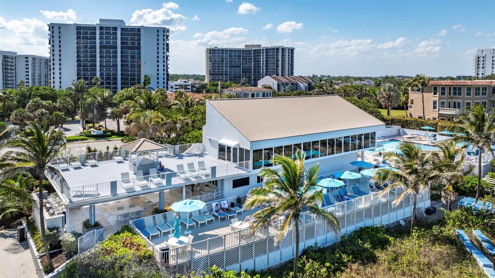 An aerial view of a white building with a metal roof, pool deck, and palm trees — 4748 S Ocean Boulevard # 502, Highland Beach FL 33487, HIGHLAND BEACH, FL