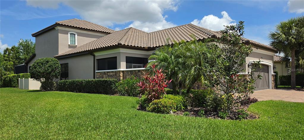 A tan house with a paved driveway, a palm tree, and manicured hedges — 9760 HIGHLAND PARK PLACE, PALMETTO, FL