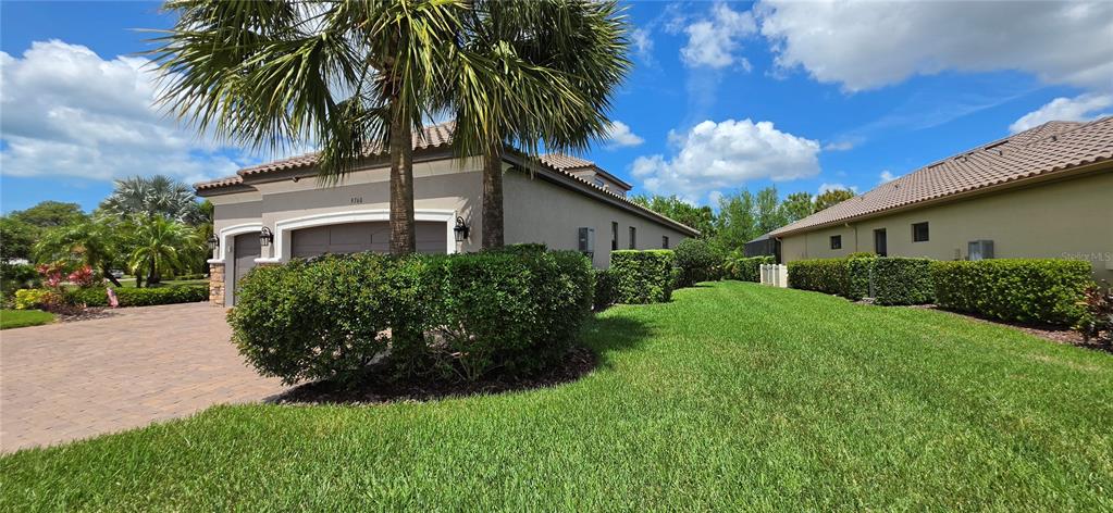 A stone-columned entryway features a black metal gate leading to a screened-in porch area — 9760 HIGHLAND PARK PLACE, PALMETTO, FL