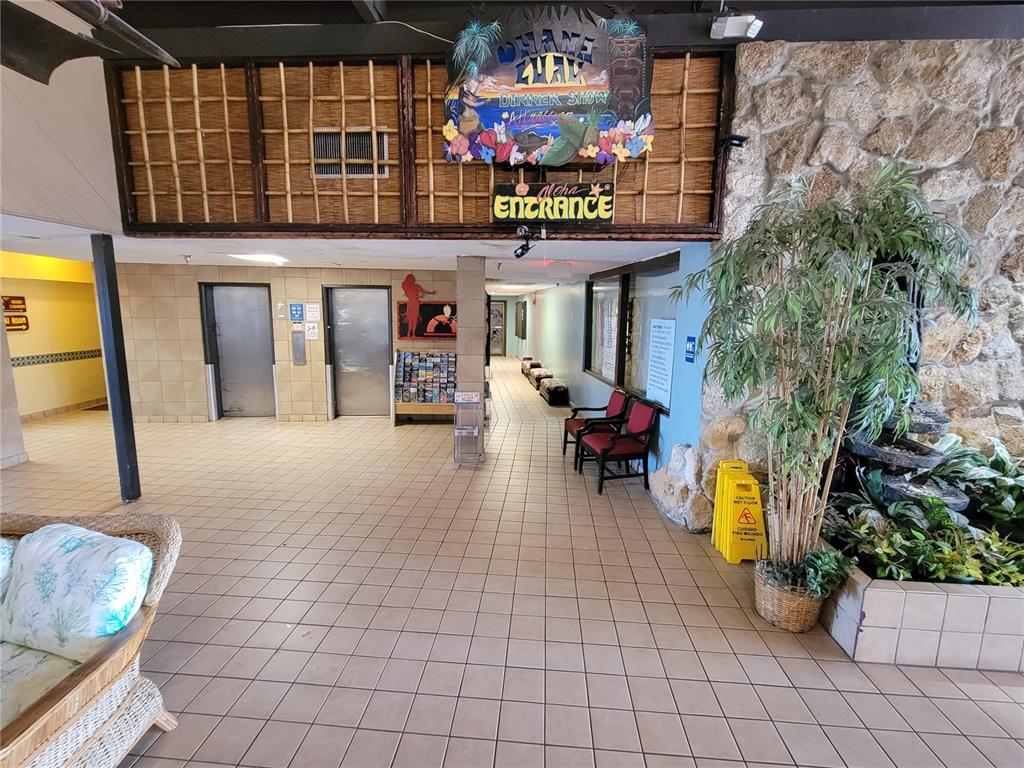 A tiled lobby features two elevators, a decorative sign, seating, and a potted plant — 2301 S ATLANTIC AVENUE UNIT 238, DAYTONA BEACH, FL
