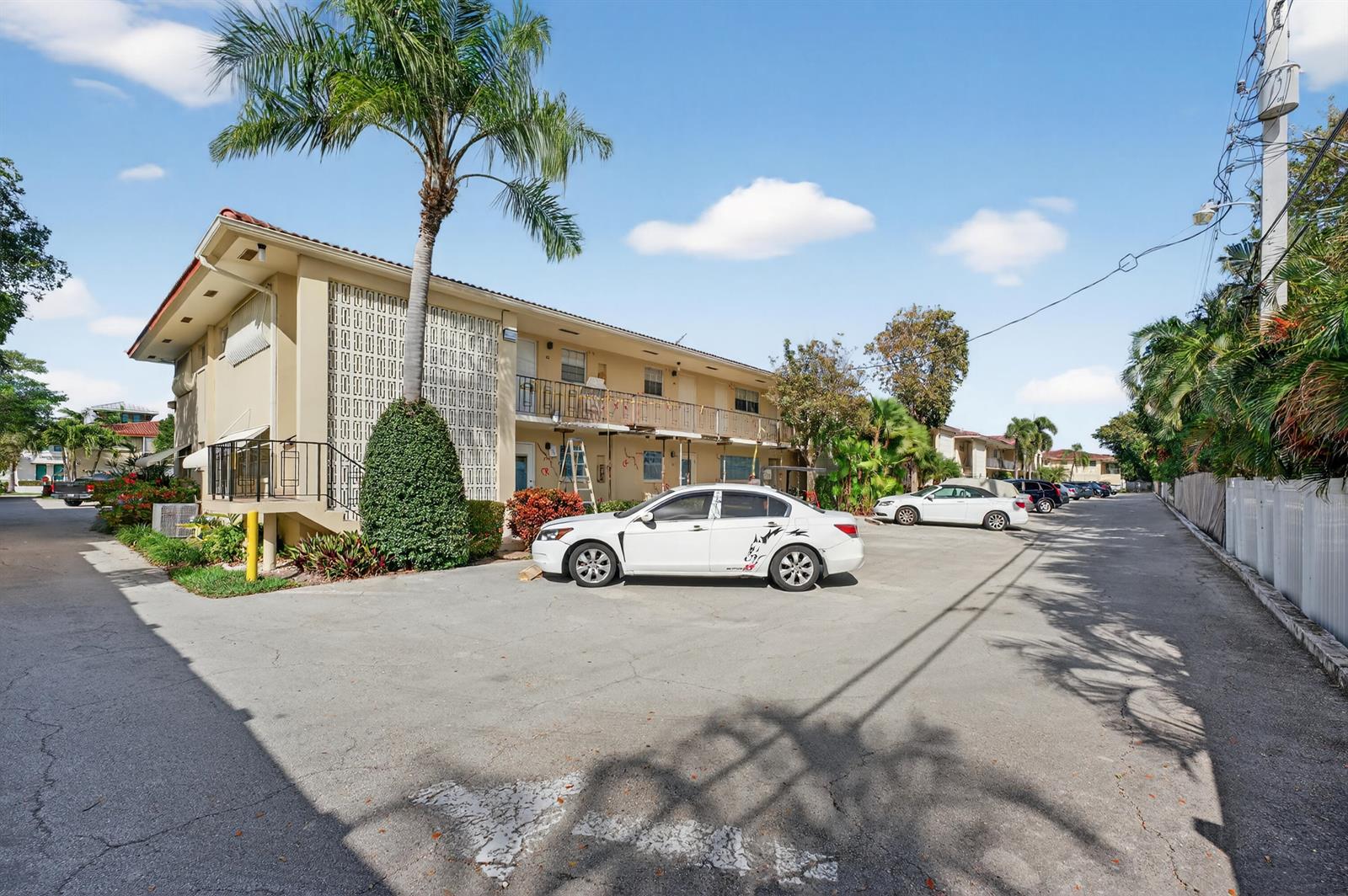 A two-story apartment building with a parking lot and a white sedan in the foreground — 2134 NE 36th Street # 82, Lighthouse Point FL 33064, LIGHTHOUSE POINT, FL