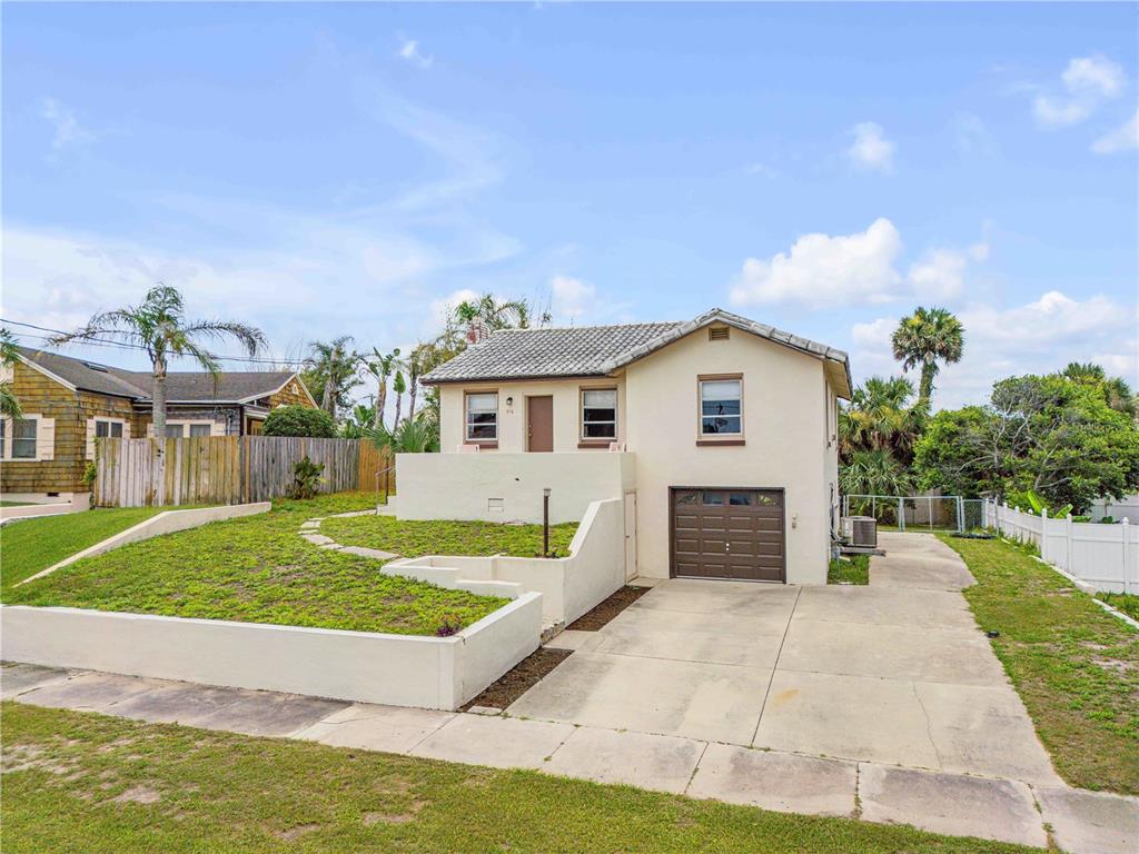 A two-story house with a beige exterior, a brown garage door, and a terraced front yard — 516 WISTERIA ROAD, DAYTONA BEACH, FL