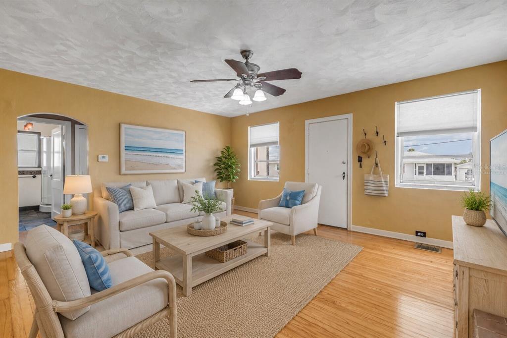 A living room with yellow walls, a light-colored sofa, two armchairs, and hardwood floors — 516 WISTERIA ROAD, DAYTONA BEACH, FL