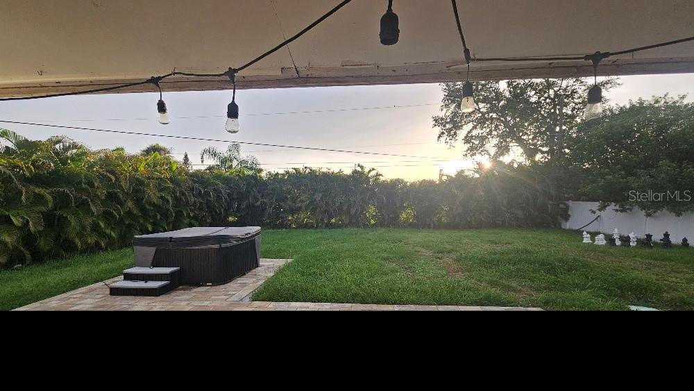 A backyard features a hot tub on a patio, a grassy lawn, and string lights — 250 CHAMBER STREET NW, PORT CHARLOTTE, FL