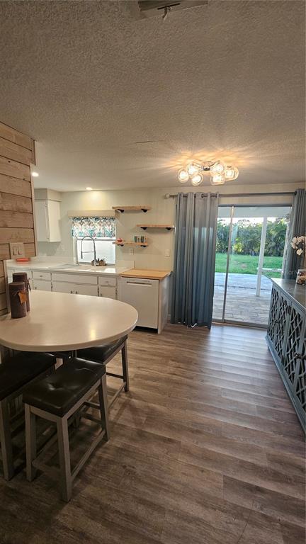 A kitchen features a breakfast bar, white cabinetry, open shelving, and a sliding glass door — 250 CHAMBER STREET NW, PORT CHARLOTTE, FL