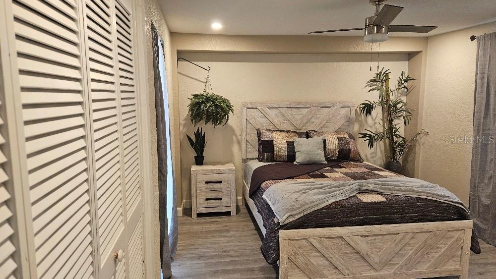 A bedroom features a wooden bed frame, a matching nightstand, and a ceiling fan — 250 CHAMBER STREET NW, PORT CHARLOTTE, FL