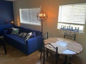 A living and dining area features a blue sofa, a round table, and a floor lamp — 3206 W AZEELE STREET UNIT 220, TAMPA, FL
