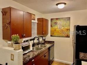 A kitchen features brown cabinets, a double sink, a microwave, and a black refrigerator — 3206 W AZEELE STREET UNIT 220, TAMPA, FL