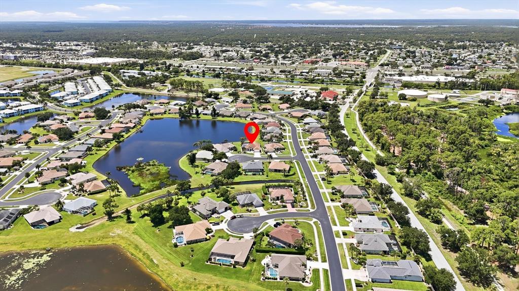 This aerial view shows a residential neighborhood with a lake and a marked house — 5376 OAKMONT COURT, NORTH PORT, FL
