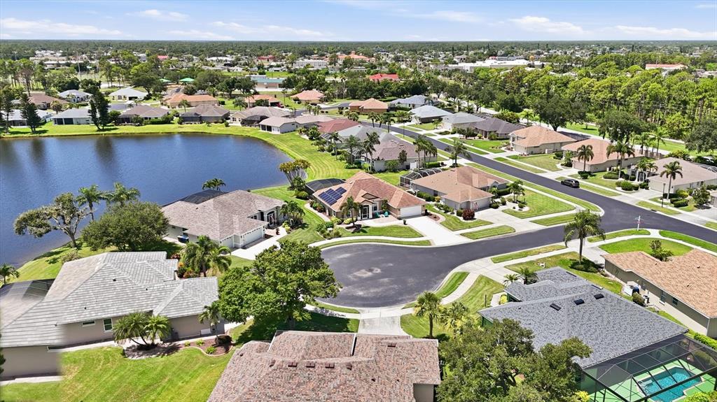 An aerial view shows a suburban neighborhood with houses surrounding a lake and cul-de-sac — 5376 OAKMONT COURT, NORTH PORT, FL