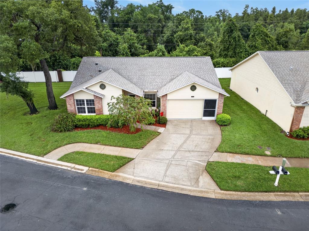 An aerial view of a single-story suburban house with a concrete driveway and green lawn — 4949 BOSTONIAN LOOP, NEW PORT RICHEY, FL