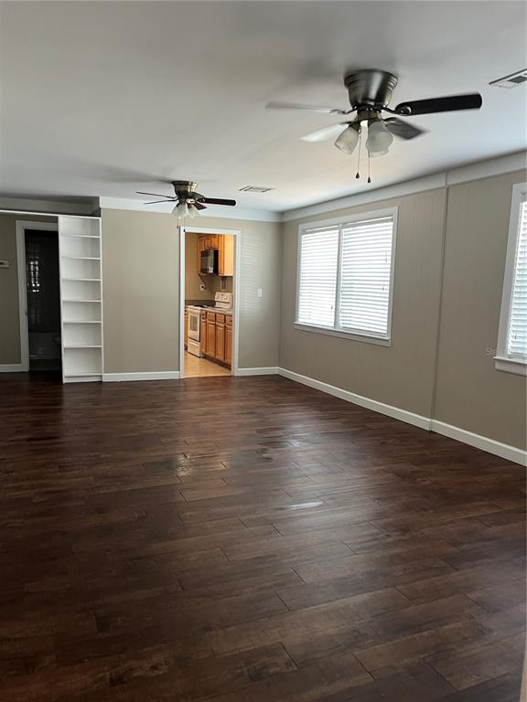 A living room with dark wood-look flooring, two ceiling fans, and an adjacent kitchen — 949 N GRANDVIEW STREET, MOUNT DORA, FL